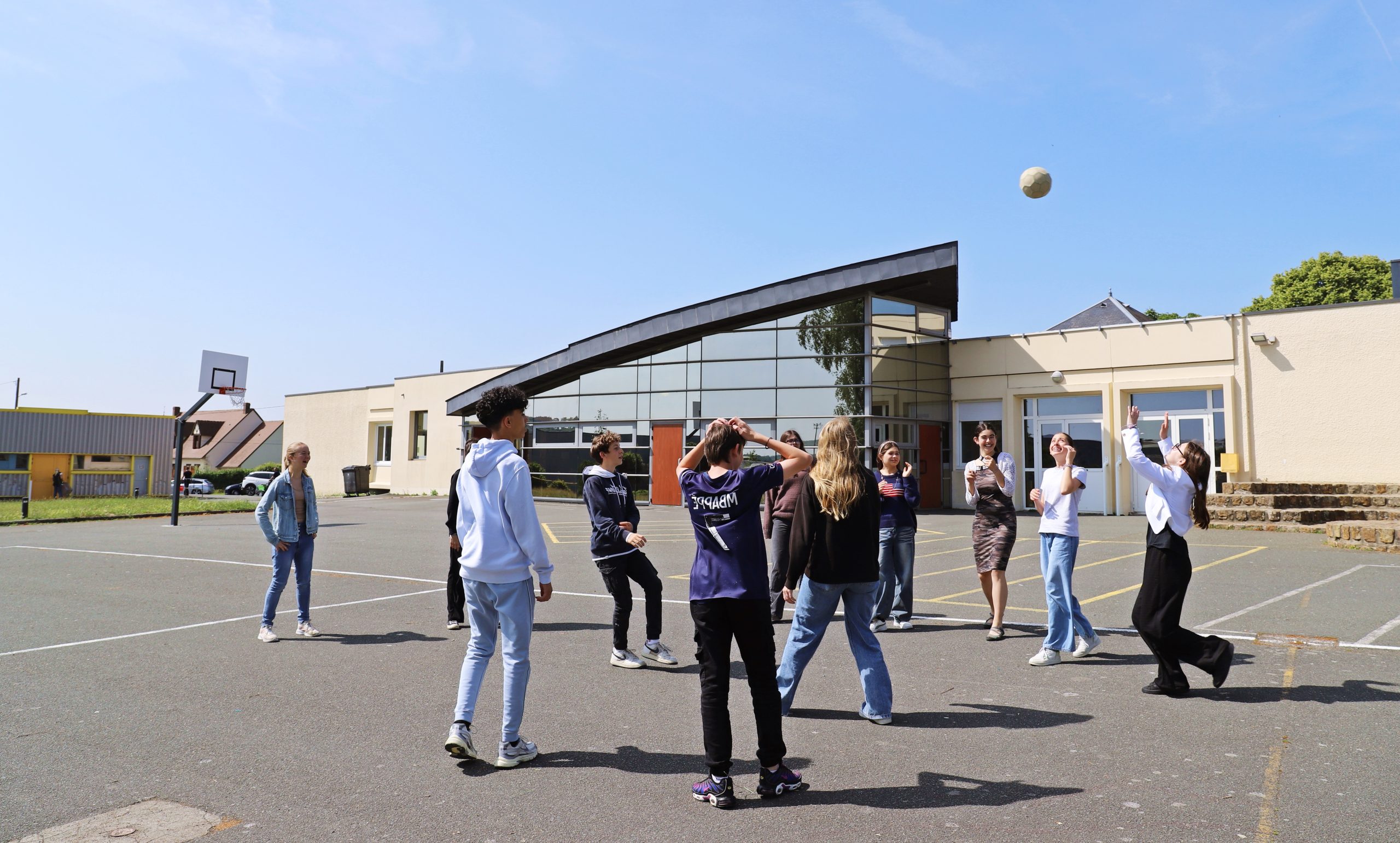 Adolescents jouent avec un ballon dans la cours du collège